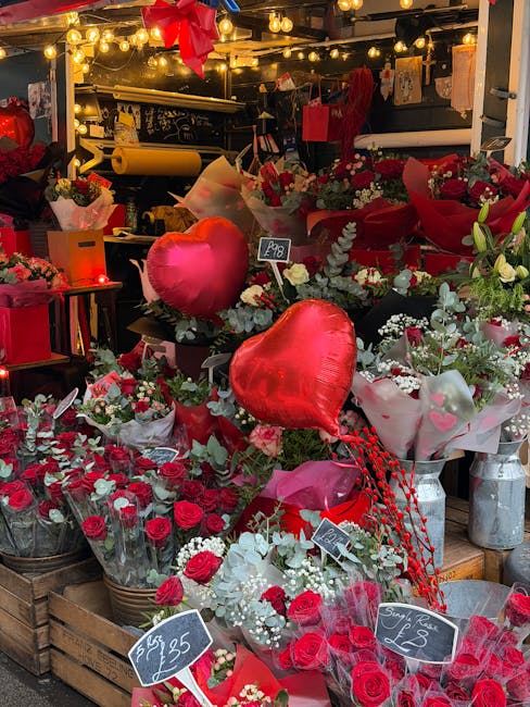 A vibrant display of fresh floral arrangements at Rayners Lane Florist, with red roses, white flowers, and greenery artistically arranged in bouquets. Prominent among the flowers are large, red foil h